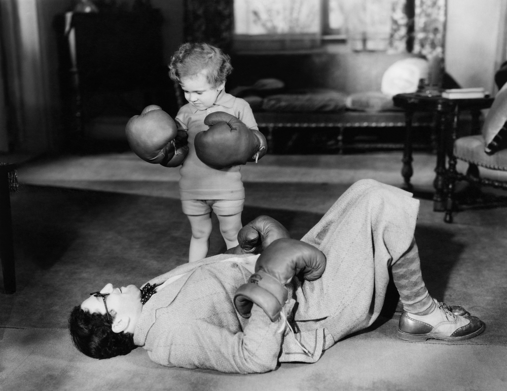 Child boxing with adult on ground