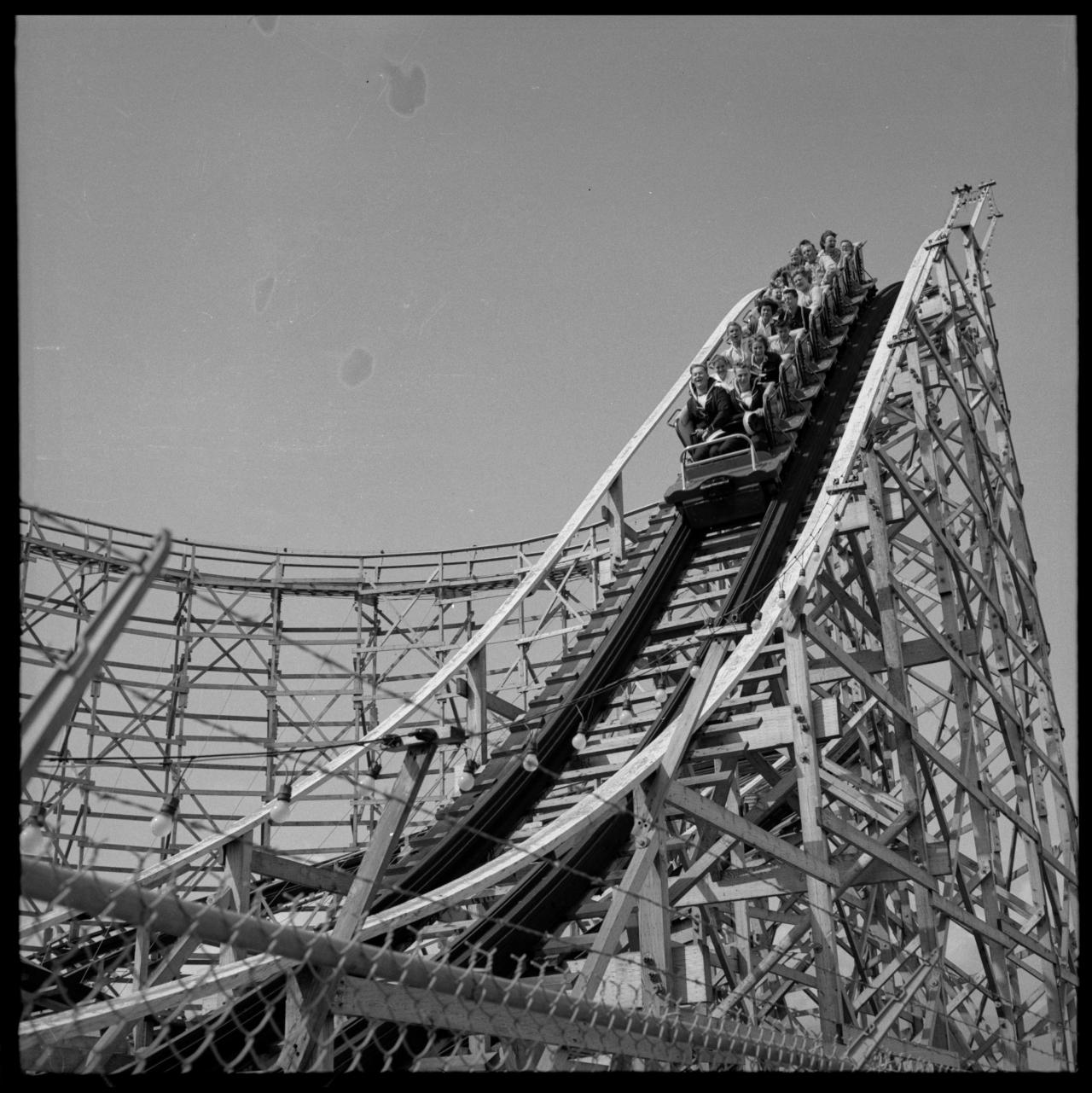 tumblr_obnbmasdbt1sfie3io1_1280 A packed wooden roller coaster car crests the top of a steep wooden truss structure, evoking the leveraged, fast-climbing debt structures financing the AI data center boom.