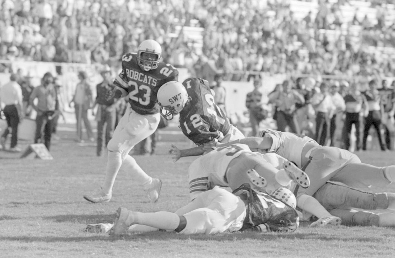 tumblr_oh9rbljstK1sfie3io1_1280 Archival black and white photograph of a football running back breaking free from a pile of tacklers, illustrating Palantir's revenue growth pulling away from the rest of the software sector