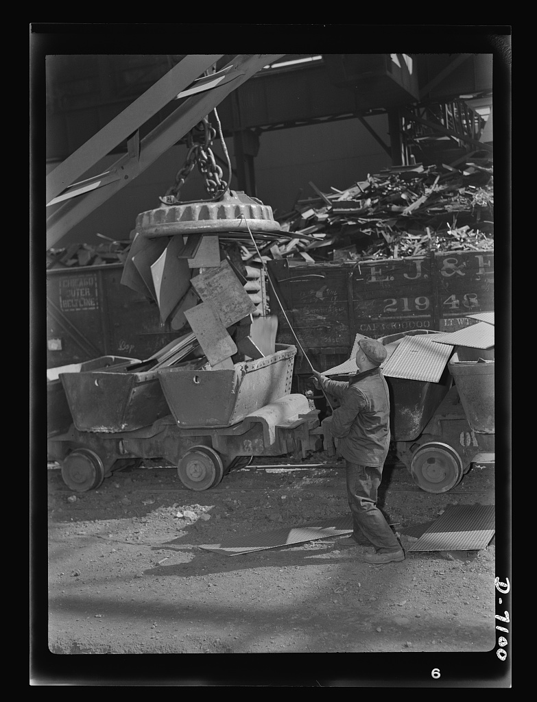 service-pnp-fsa-8b07000-8b07700-8b07775v Archival black and white photo of a worker loading freight crates with a crane, illustrating Amazon's logistics and warehouse operations